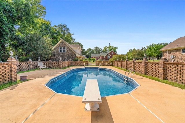 view of swimming pool with a diving board and a patio