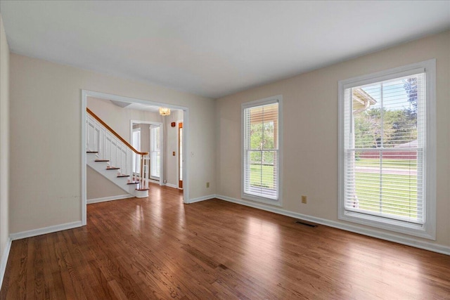 spare room with hardwood / wood-style floors and an inviting chandelier