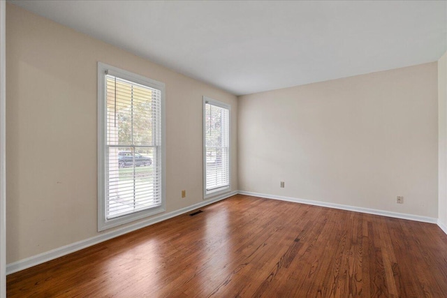 spare room with dark wood-type flooring and a healthy amount of sunlight