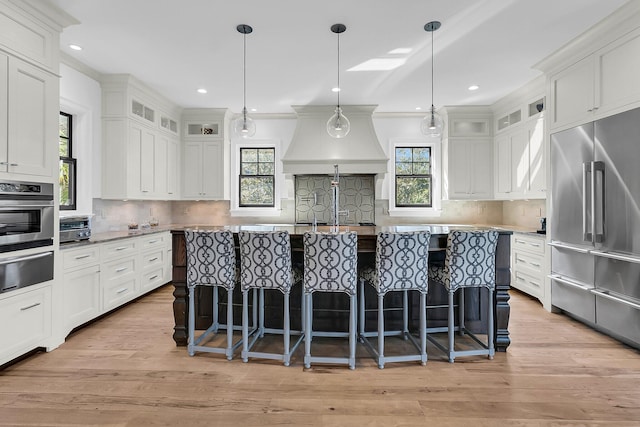 kitchen with white cabinetry, light hardwood / wood-style floors, stainless steel appliances, and hanging light fixtures