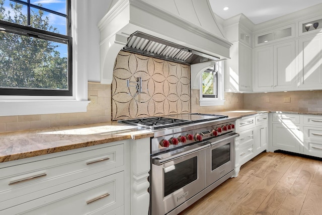 kitchen with light hardwood / wood-style floors, white cabinetry, light stone counters, and double oven range