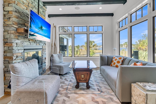 sunroom / solarium with a stone fireplace, beam ceiling, and plenty of natural light