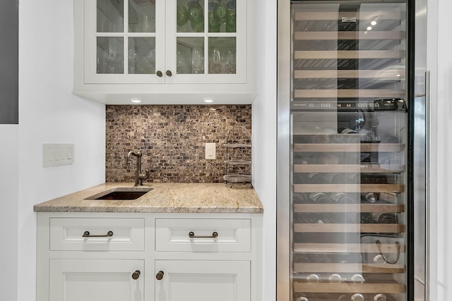 bar featuring light stone countertops, sink, backsplash, white cabinetry, and wine cooler