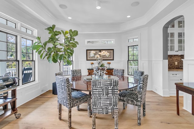 dining area featuring ornamental molding, light wood-type flooring, and a raised ceiling