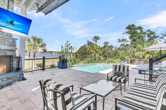 view of swimming pool with a patio and an outdoor stone fireplace