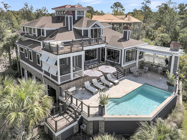 back of house with a balcony, a patio, and a sunroom