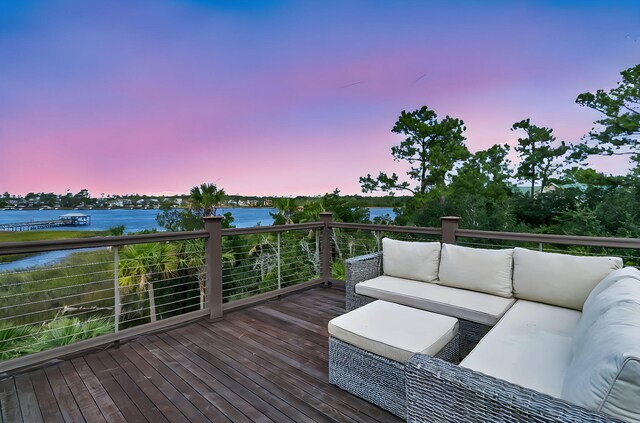 deck at dusk with an outdoor living space and a water view