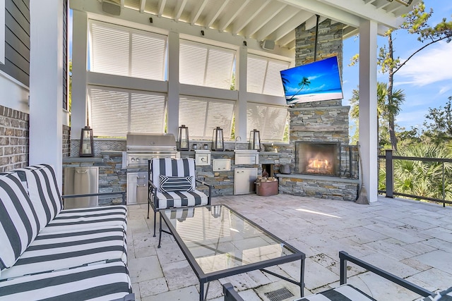 view of patio / terrace with area for grilling, an outdoor stone fireplace, and exterior kitchen