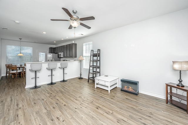 kitchen featuring a peninsula, light wood-style floors, appliances with stainless steel finishes, and a breakfast bar