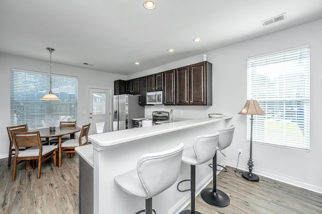 kitchen featuring light countertops, appliances with stainless steel finishes, visible vents, and a kitchen breakfast bar