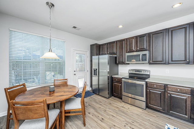 kitchen with pendant lighting, stainless steel appliances, dark brown cabinetry, and light wood-style floors