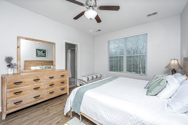 bedroom with a ceiling fan, visible vents, and wood finished floors