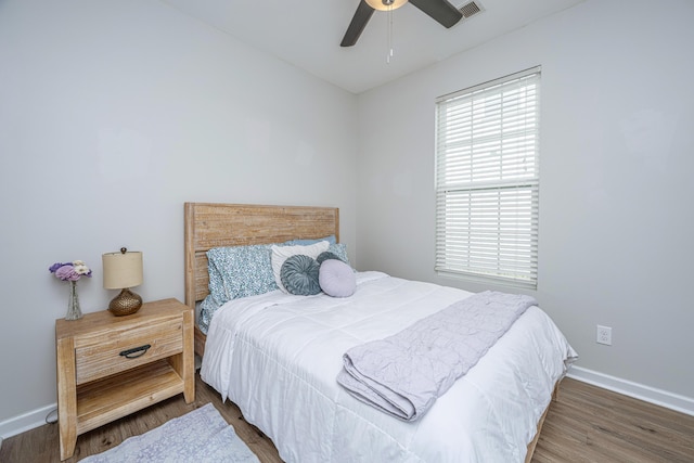 bedroom featuring baseboards, visible vents, ceiling fan, and wood finished floors