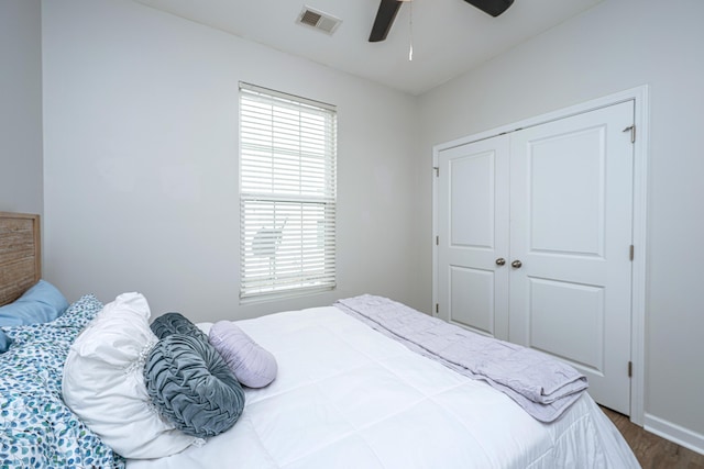 bedroom with multiple windows, visible vents, dark wood-type flooring, and a closet