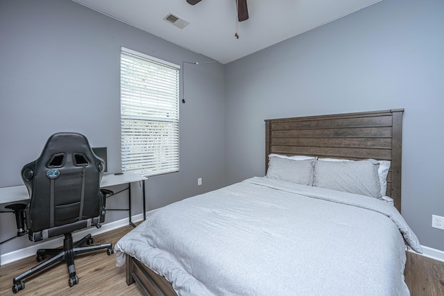 bedroom with baseboards, visible vents, vaulted ceiling, and wood finished floors