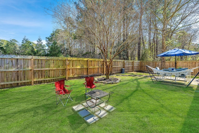 view of yard with a fenced backyard and a fire pit