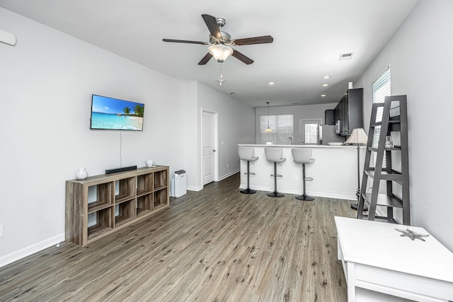 living room featuring light wood-style floors, ceiling fan, baseboards, and recessed lighting