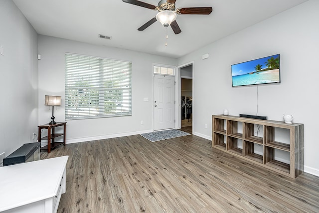 living area with baseboards, visible vents, and wood finished floors