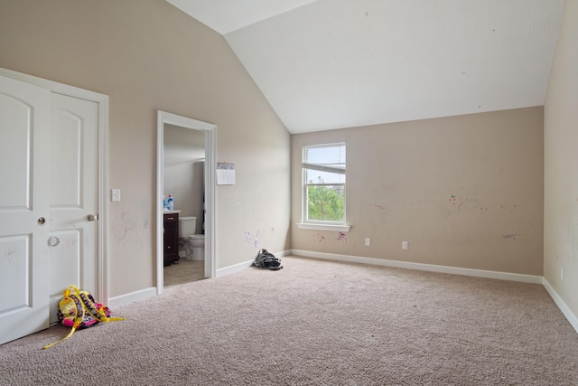 unfurnished bedroom featuring carpet flooring, ensuite bath, and lofted ceiling