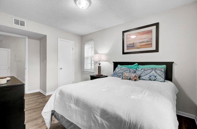 bedroom with a textured ceiling and wood-type flooring