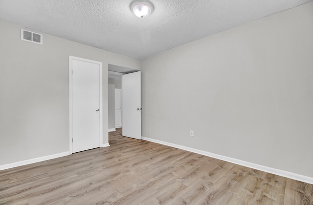 empty room with a textured ceiling and light wood-type flooring