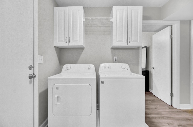 washroom featuring cabinets, light hardwood / wood-style flooring, and washer and dryer