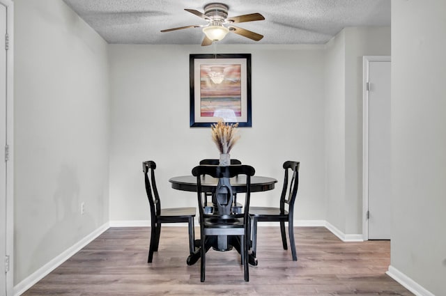 dining space with ceiling fan, a textured ceiling, and hardwood / wood-style flooring