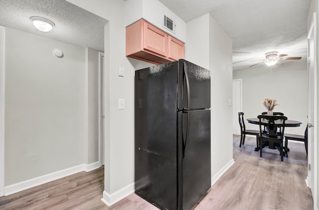 kitchen with ceiling fan, a textured ceiling, light wood-type flooring, and black fridge