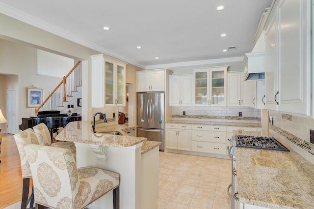 kitchen with stainless steel appliances, a sink, light stone countertops, backsplash, and recessed lighting