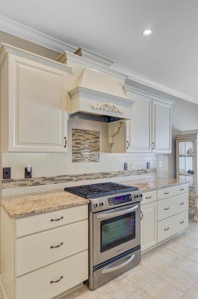 kitchen featuring stainless steel range with gas cooktop, ornamental molding, backsplash, custom range hood, and light stone countertops