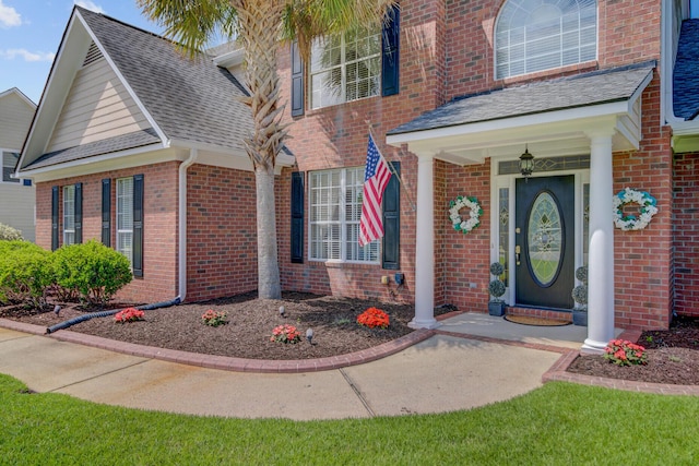 view of front of property featuring brick siding and roof with shingles
