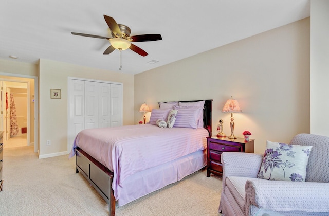 bedroom with a closet, light colored carpet, ceiling fan, and baseboards