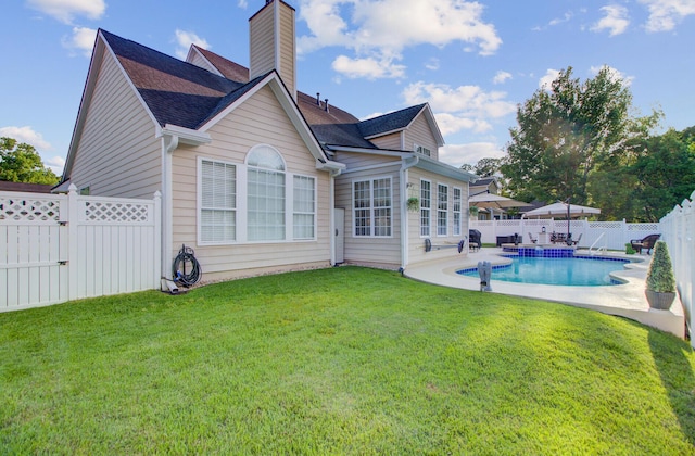 back of house featuring a chimney, a patio area, and a shingled roof