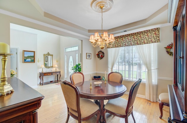 dining space with a raised ceiling, a chandelier, light wood-style flooring, and baseboards