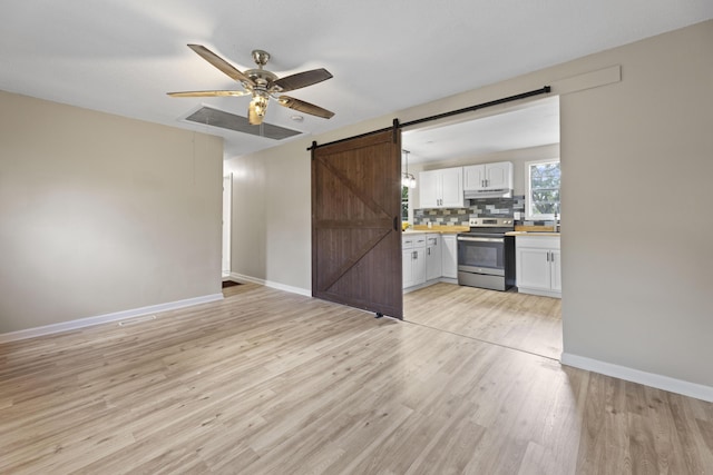 121 Harrison St, Varnville, SC 29944 - unfurnished living room featuring a barn door, a ceiling fan, baseboards, and light wood-type flooring