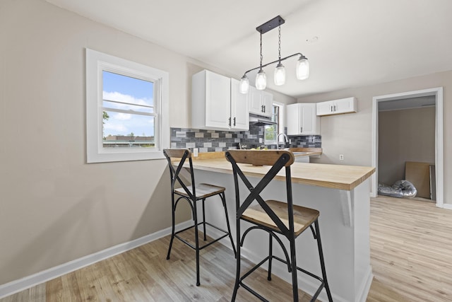 121 Harrison St, Varnville, SC 29944 - kitchen with a peninsula, wood counters, light wood-style floors, a kitchen breakfast bar, and backsplash