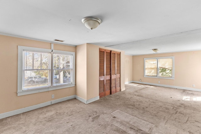 carpeted spare room featuring visible vents and baseboards