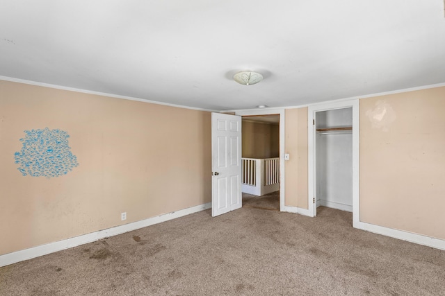 unfurnished bedroom with crown molding, a closet, carpet, and baseboards