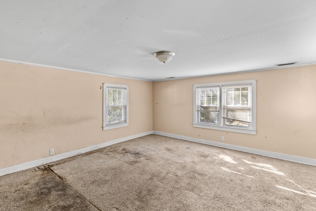 spare room featuring carpet floors, baseboards, visible vents, and a wealth of natural light