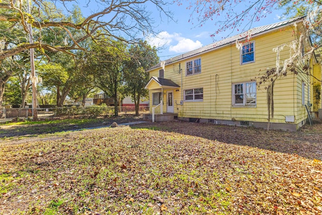 view of front of home with crawl space, fence, and metal roof