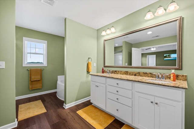 3055 Matthews Dr, Sumter, SC 29154 - full bathroom featuring wood finished floors, a bathtub, baseboards, double vanity, and a ceiling fan