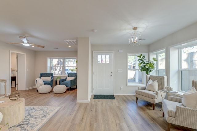 entrance foyer with ceiling fan with notable chandelier and light hardwood / wood-style floors