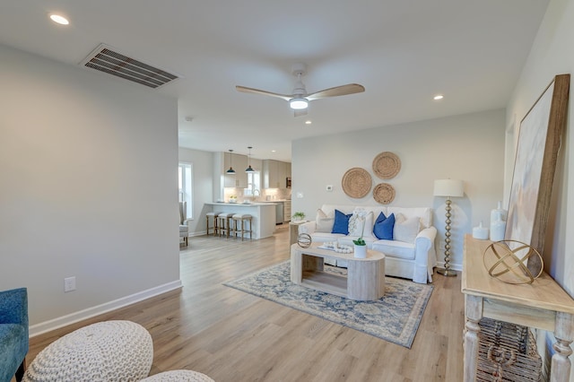 living room with ceiling fan and light hardwood / wood-style flooring