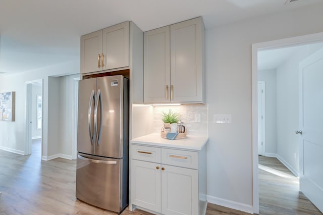 kitchen with light hardwood / wood-style floors, stainless steel refrigerator, and tasteful backsplash