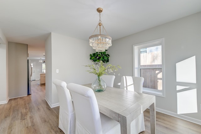 dining space featuring light hardwood / wood-style floors and an inviting chandelier