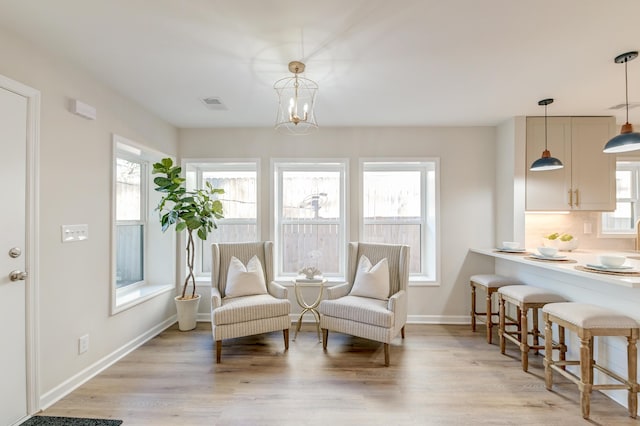 sitting room with a chandelier, light hardwood / wood-style floors, and a healthy amount of sunlight