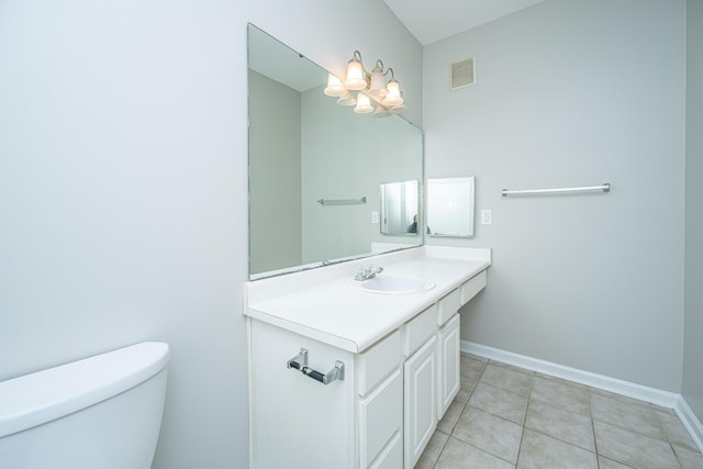 bathroom with toilet, vanity, and tile patterned flooring