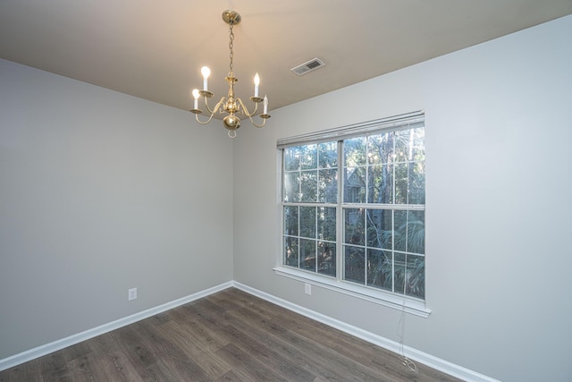 empty room with dark wood-type flooring and a chandelier