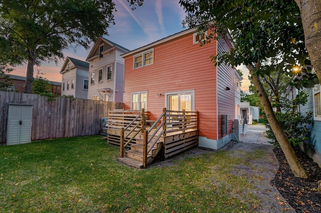 rear view of house with a lawn, fence, and a deck