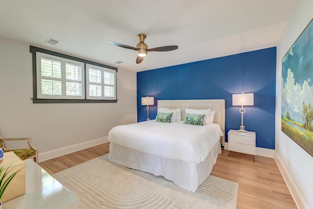 bedroom with baseboards, a ceiling fan, wood finished floors, and visible vents